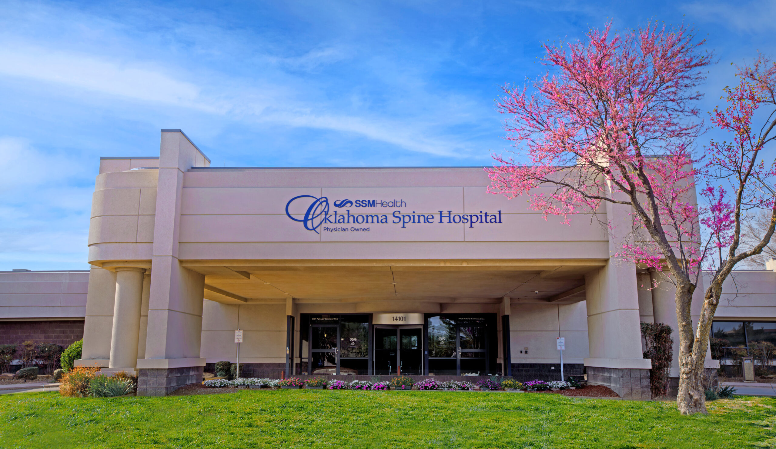 Front entrance of SSM Health Oklahoma Spine Hospital with blooming tree and landscaped grounds